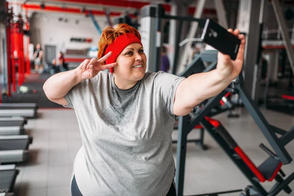 肥胖的出汗妇女采取自拍反对运动机器在健身房 — 图库照片
