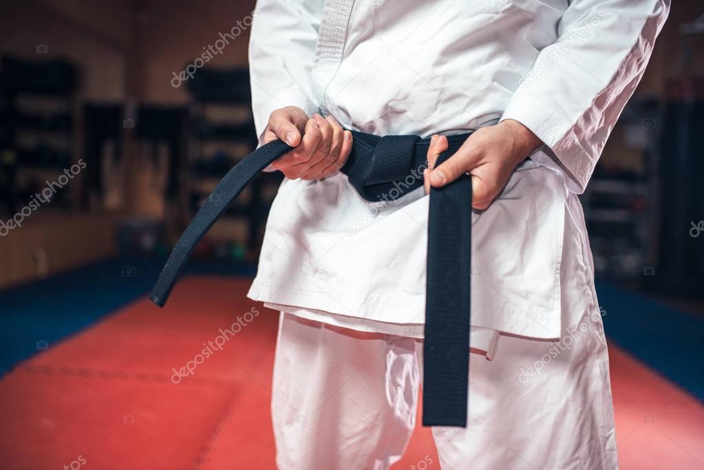 fighter in white kimono with black belt, karate training in gym