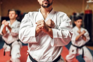 Dövüş sanatları karate ustası ve öğrencileri beyaz üniforma ve siyah bantlar, mücadele eğitim salonunda