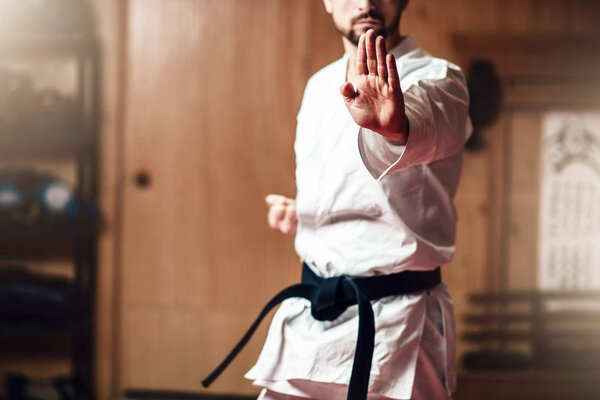 fighter in white kimono with black belt, karate training in gym