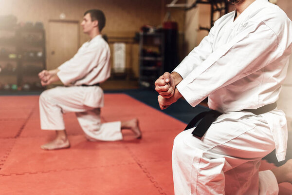 Martial arts karate masters in white kimono and black belts, fight training in gym