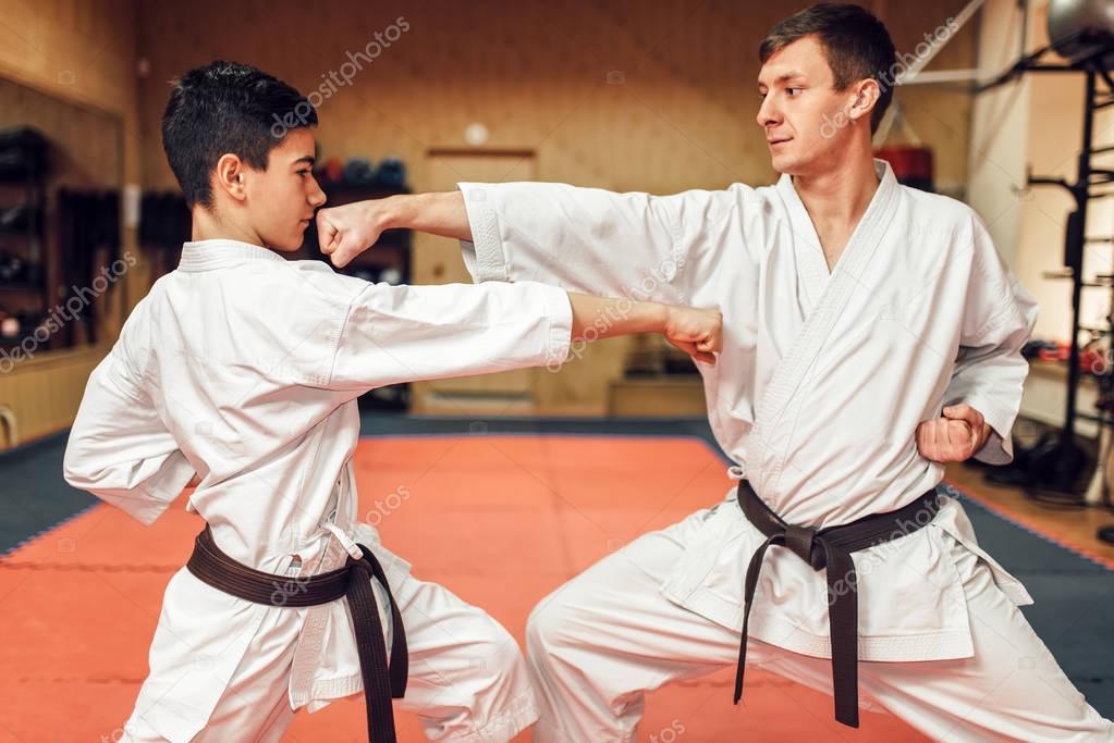 Martial arts karate masters in white kimono and black belts, fight training in gym