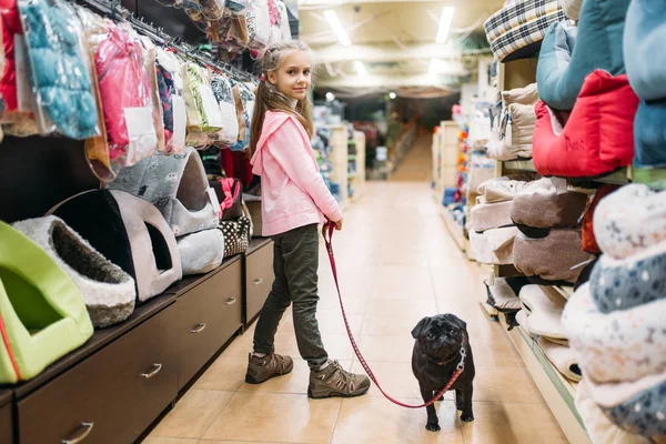 little girl playing with puppy in pet shop, friendship