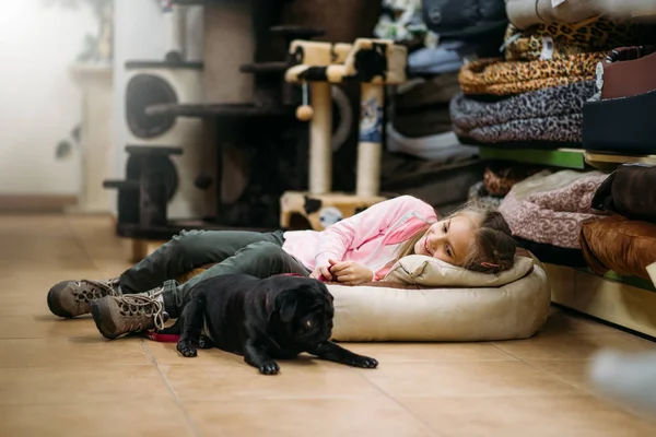 little girl with puppy sleeping in pet shop