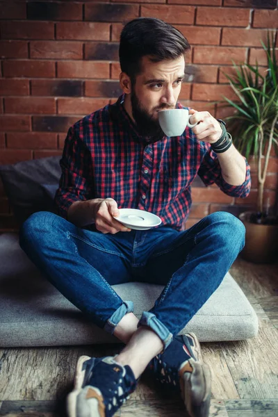 young man sitting in coffee house drinking beverage