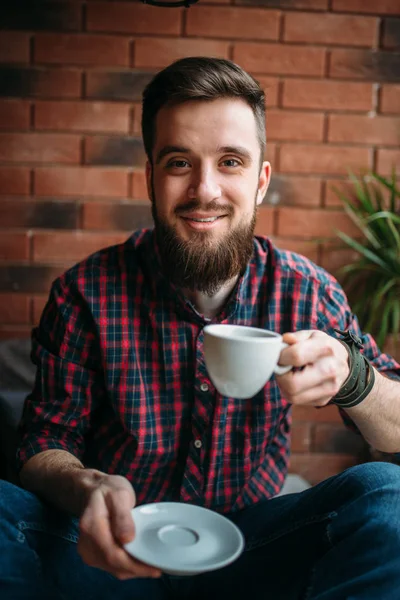 飲み物を飲むコーヒー家に座っている若い男 — ストック写真