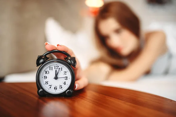 woman stopping alarm clock, waking up concept