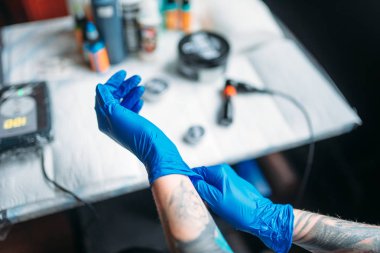 kadın dövme sanatçısı mavi steril eldiven, profesyonel çalışma araçlar arka plan üzerinde eller. Salonda dövme