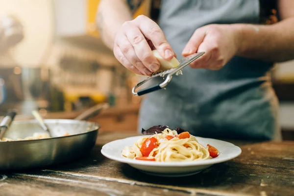 Männerkoch Reibt Käse Mit Frisch Gekochten Nudeln Auf Den Teller — Stockfoto