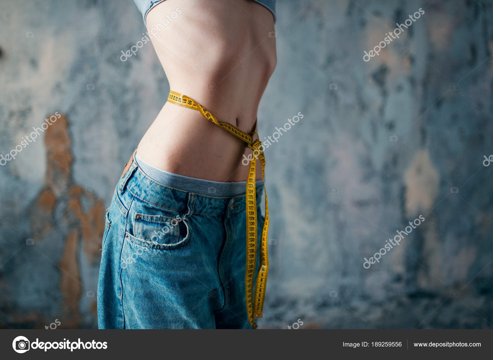 Thin woman in jeans measures waist, weight loss Stock Photo by