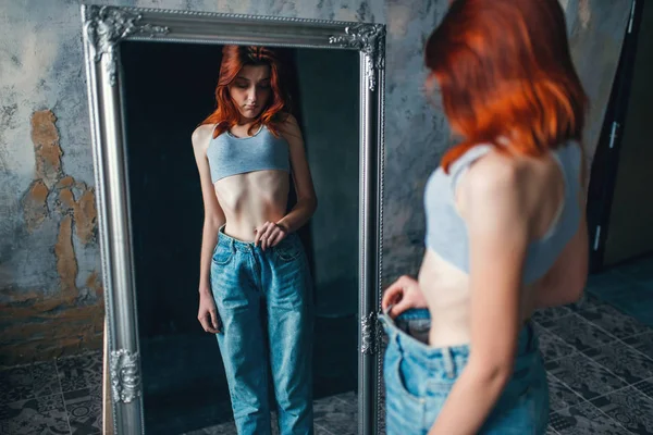 瘦女人试穿大尺寸的牛仔裤对镜子 体重下降 厌食症 — 图库照片