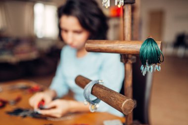 Iğne işi, aksesuarlar, bilezik, atölye arka plan olarak işyerinde kadın efendi ile sahibi