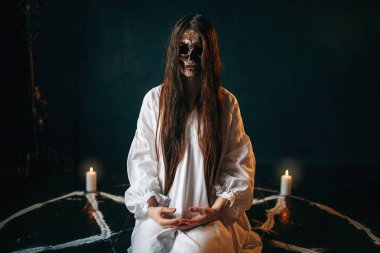 Kafatası kafasıyla mumlar ile bir pentagram dairede oturan kadın cadı