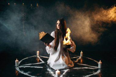 Beyaz gömlek okuma büyü, mumlar, karanlık büyü ayini olan pentagram daire cadı. Büyü ve şeytan çıkarma