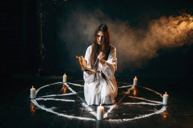 Cadı Beyaz gömlekli bıçak ve okuma büyü, mumlar, karanlık büyü ayini olan pentagram daire tutar. Büyü ve şeytan çıkarma