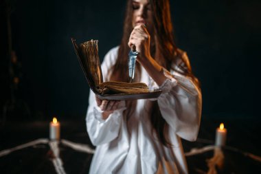 Beyaz gömlekli holding bıçak ve okuma büyü, mumlar, kara büyü ritüel işlemi olan pentagram daire cadı