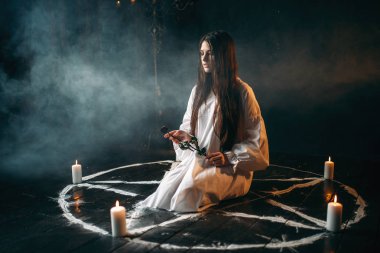 genç kadın tutan eller, mumlar ve duman, kara büyü ritüel, pentagram daireyle gül yanmış yöneltici