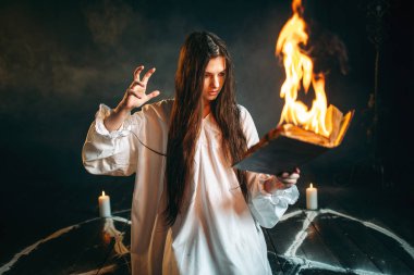 Beyaz gömlek okuma büyü, mumlar, karanlık büyü ayini olan pentagram daire cadı. Büyü ve şeytan çıkarma