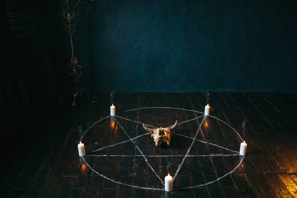 pentagram circle with candles on black wooden floor. Dark magic ritual with occult and esoteric symbols