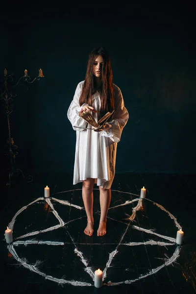 キャンドルと呪文 暗黒魔法儀式 オカルティズムを読んで五芒星サークルの中央に白いシャツの若い女性 — ストック写真