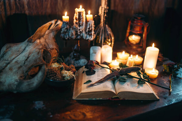 witchcraft, dark magic, candles with ritual book on table,occult and esoteric symbols