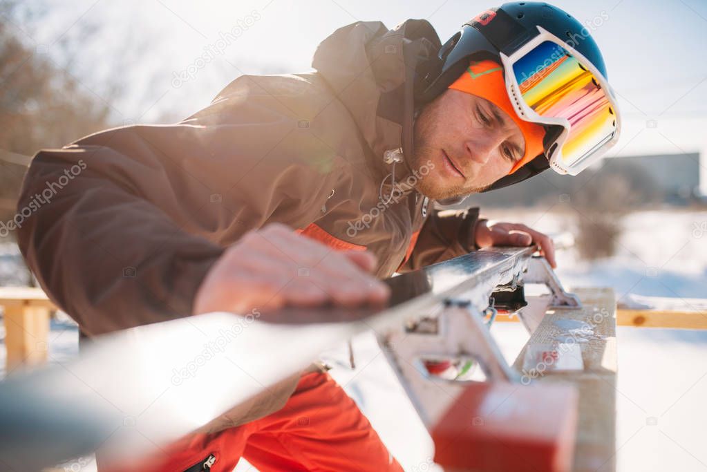 male skier checking skis before skiing, winter active sport