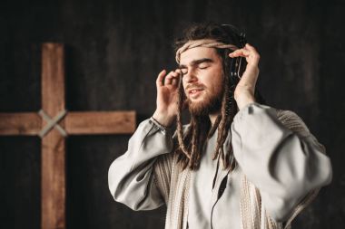 İsa Mesih, kulaklık ile müzik dinlemek çarmıha çapraz siyah arka plan üzerine. Mümin ve modern teknolojileri kavramı
