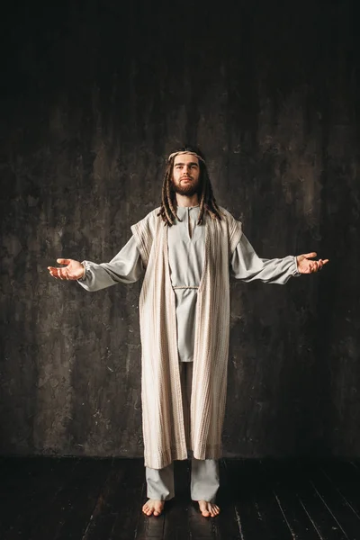 Jesus Christ with open arms, dark background, Christian faith, son of God