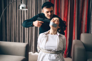 Katil silahı ile siyah giysili kadın kurbanı vurmaya çalışıyor ile ip ve bant sandalyeye bağlı