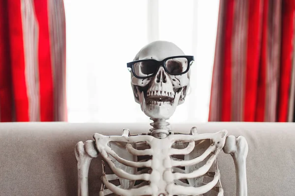 Esqueleto Sorridente Óculos Está Sentado Sofá Janela Cortinas Vermelhas Fundo — Fotografia de Stock