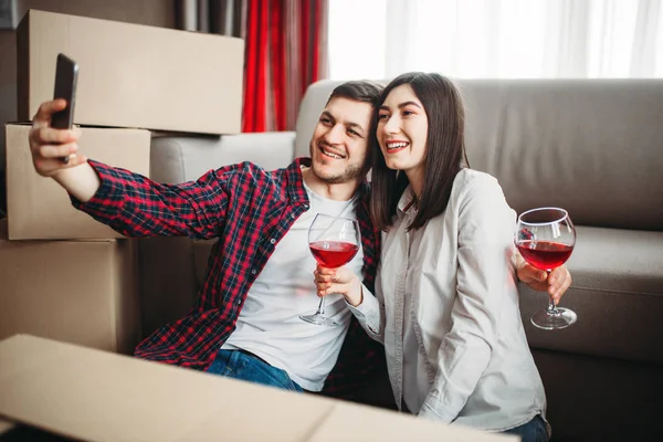 年轻夫妇采取自拍对纸板箱 搬到新房 搬迁到公寓庆祝 — 图库照片