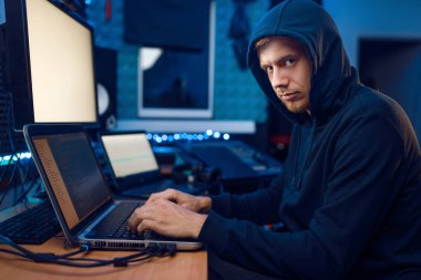 Kaputta oturan bilgisayar korsanı, bilgi hackleme. İnternet casusu, şifreli bir ağı hacklemeye çalışan erkek programcı.