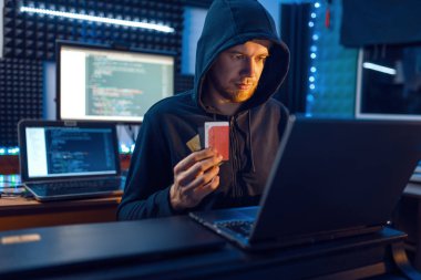 Mahalledeki bilgisayar korsanı, iş yerinde bilgisayar ve masaüstü bilgisayarı, şifre ya da finans hacklemesi, darknet kullanıcısı olan bir banka kartı gösteriyor. İnternet casusu, suç yaşam tarzı, risk işi, ağ suçlusu