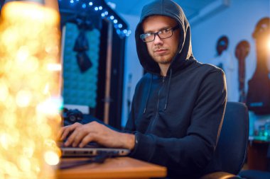 Bilgisayarı ve masaüstü bilgisayarı olan kapüşonlu bir bilgisayar korsanı, web sitesi ya da şirket hacklemesi, darknet kullanıcısı. İnternet casusu, suç yaşam tarzı, risk işi, ağ suçlusu