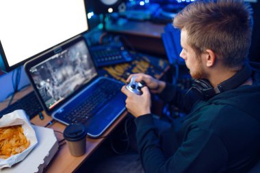 Kulaklıklı erkek oyuncu joystick 'i tutuyor ve konsol veya masaüstü bilgisayarında bilgisayar oyunu oynuyor, oyun yaşam tarzı, siber spor. Odasında neon ışıklı, flamalı bilgisayar oyunları oynatıcı