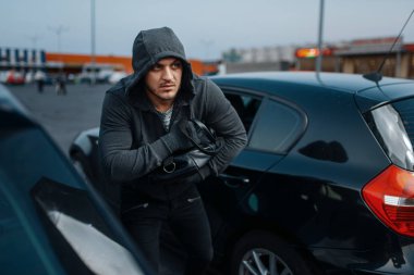 Araba hırsızı kadın çantası, suç yaşam tarzı, hırsızlık alır. Kapüşonlu erkek haydut aracı park yerinde açılıyor. Otomobil soygunu, otomobil suçu
