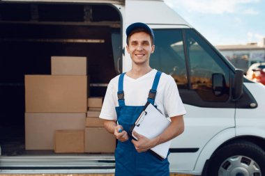 Üniformalı teslimatçı, arabada karton kutular, teslimat servisi. Karton paketlerin başında duran bir adam araç, erkek teslimatı, kurye ya da nakliye işi