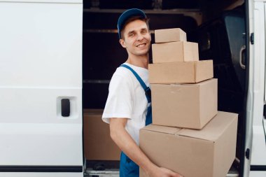 Üniformalı postacı paketleri, teslimat hizmetlerini arabaya boşaltır. Karton paketlerin başında duran bir adam araç, erkek teslimatı, kurye ya da nakliye işi