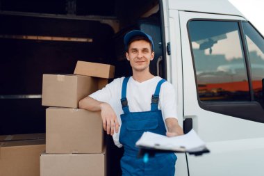 Deliveryman in uniform holding parcel and notebook, carton boxes in the car, delivery service. Man standing at cardboard packages in vehicle, male deliver clipart