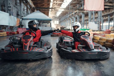Başlangıç çizgisinde iki kart yarışçısı, ön görüş, kapalı alanda karting otomobil sporu. Lastik bariyeriyle yakın go-cart pistinde hız yarışı. Hızlı araç yarışması, yüksek adrenalin eğlencesi.