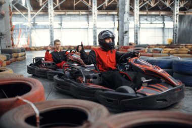 İki kart yarışçısı, kapalı alanda otomobil sporu yapıyor. Lastik engelli go-kart pistinde hız yarışı. Hızlı araç yarışması, aktif hobi