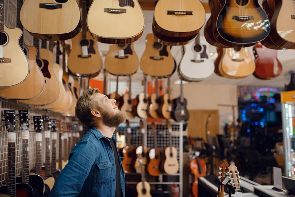 Baard Jongeman Die Akoestische Gitaar Kiest Muziekwinkel Assortiment Muziekinstrumentenwinkel Mannelijke — Stockfoto