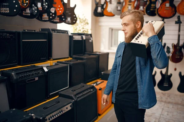 ミュージックストアでエレキギター用のコンボアンプを選択している若者 楽器店での品揃え 男性音楽家購入機器 — ストック写真