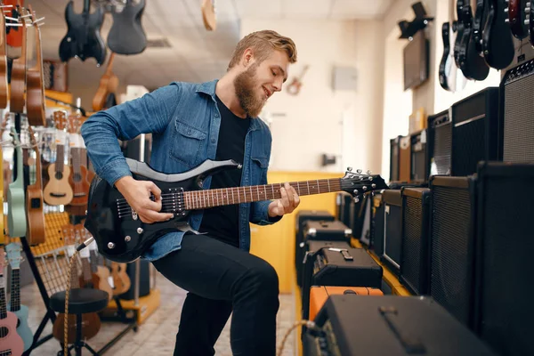 男性ギタリストはミュージックストアでエレキギターを演奏する 楽器店での品揃え 楽器を購入する音楽家 — ストック写真