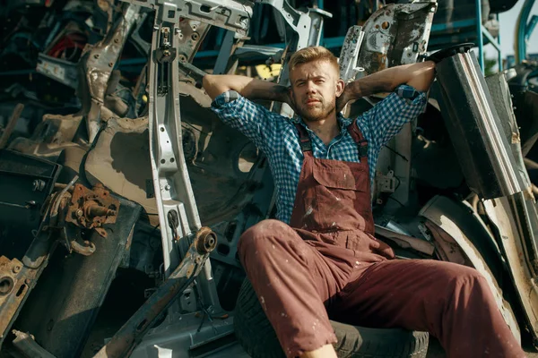 夏の日に車の上でリラックス男性修理人 自動車のスクラップ 車両のジャンク 自動車のゴミ 放棄された 破損し 粉砕輸送 — ストック写真