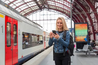 Tren istasyonunda telefonu olan kadın turist, Avrupa 'ya gidiyor. Avrupa demiryolları, konforlu turizm ve seyahat