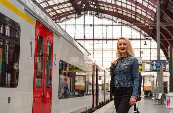 バックパック鉄道駅のプラットフォーム上の列車を待っている女性の観光客 ヨーロッパでの旅行 ヨーロッパの鉄道による交通 快適な観光 — ストック写真