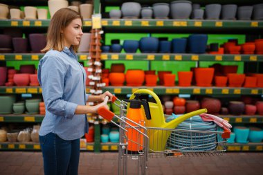 Bahçe işleri için alışveriş arabası alan kadın müşteri. Çiçekçilik, çiçekçi enstrümanı almak için malzeme seçen bir kadın.