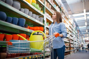 Bahçe işleri için alışveriş arabası alan kadın müşteri. Çiçekçilik için malzeme seçen bir kadın.