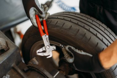 Özel makinede otomatik mekanik denge çarkı, lastik servisi. Garajda araba lastiği tamir eden adam, atölyede profesyonel otomobil denetimi